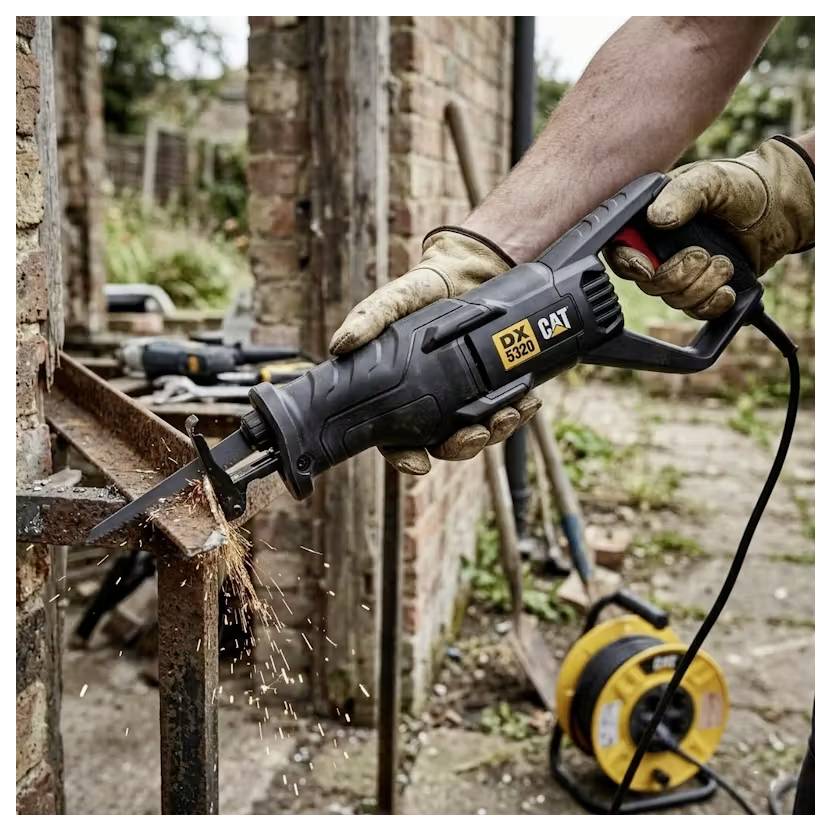 Gloved hands use a power reciprocating saw to cut a rusted metal beam outdoors, with sparks flying.