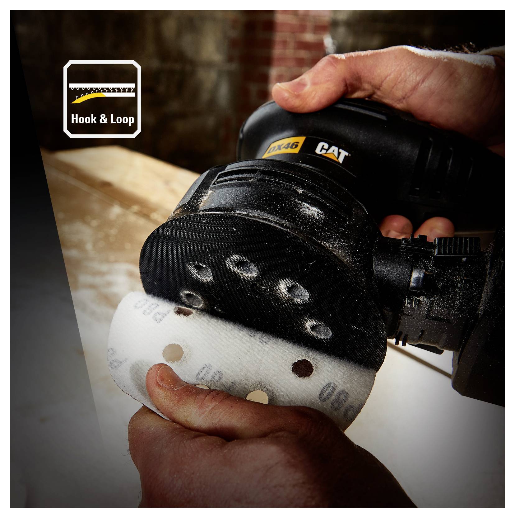 Hands sanding a curved wooden surface with a CAT power sander and hook-and-loop sanding disc.