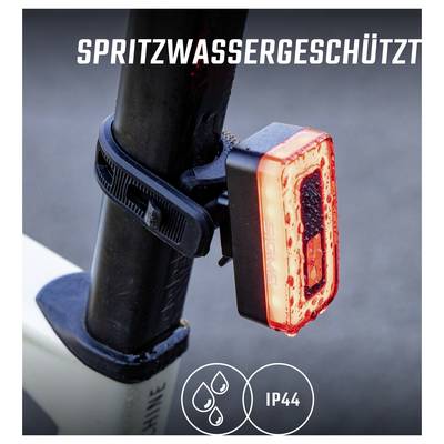 Close-up of a red bicycle rear light mounted on the frame with the imprint 'SPLASH WATER PROTECTED' and marking 'IP44'.