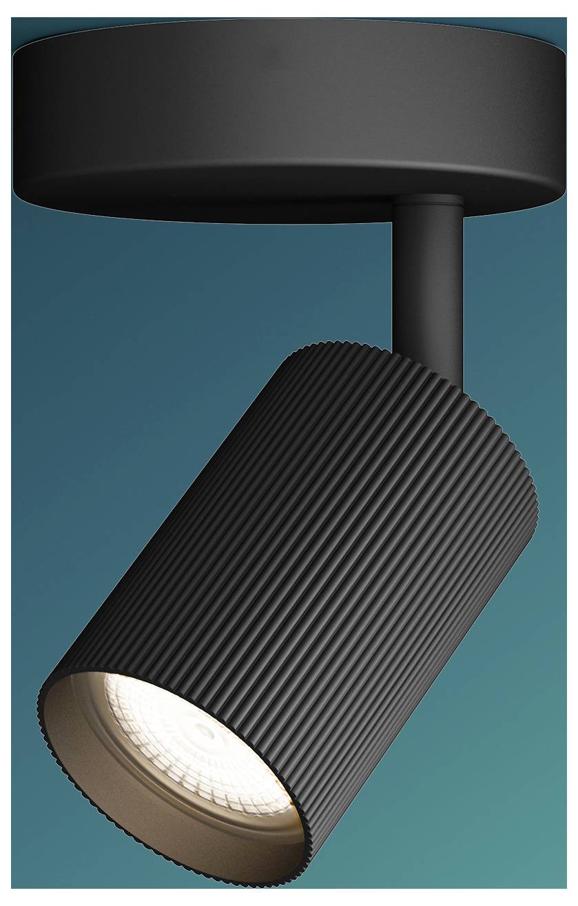 Black cylindrical spotlight mounted on a ceiling track, angled downward and lit against a teal background.