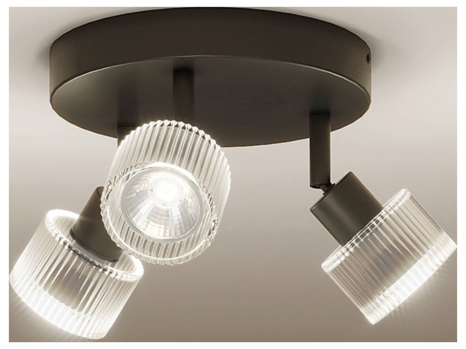 Three-bulb ceiling track light with a dark round mount and adjustable ribbed glass shades, one centered and two angled outward.