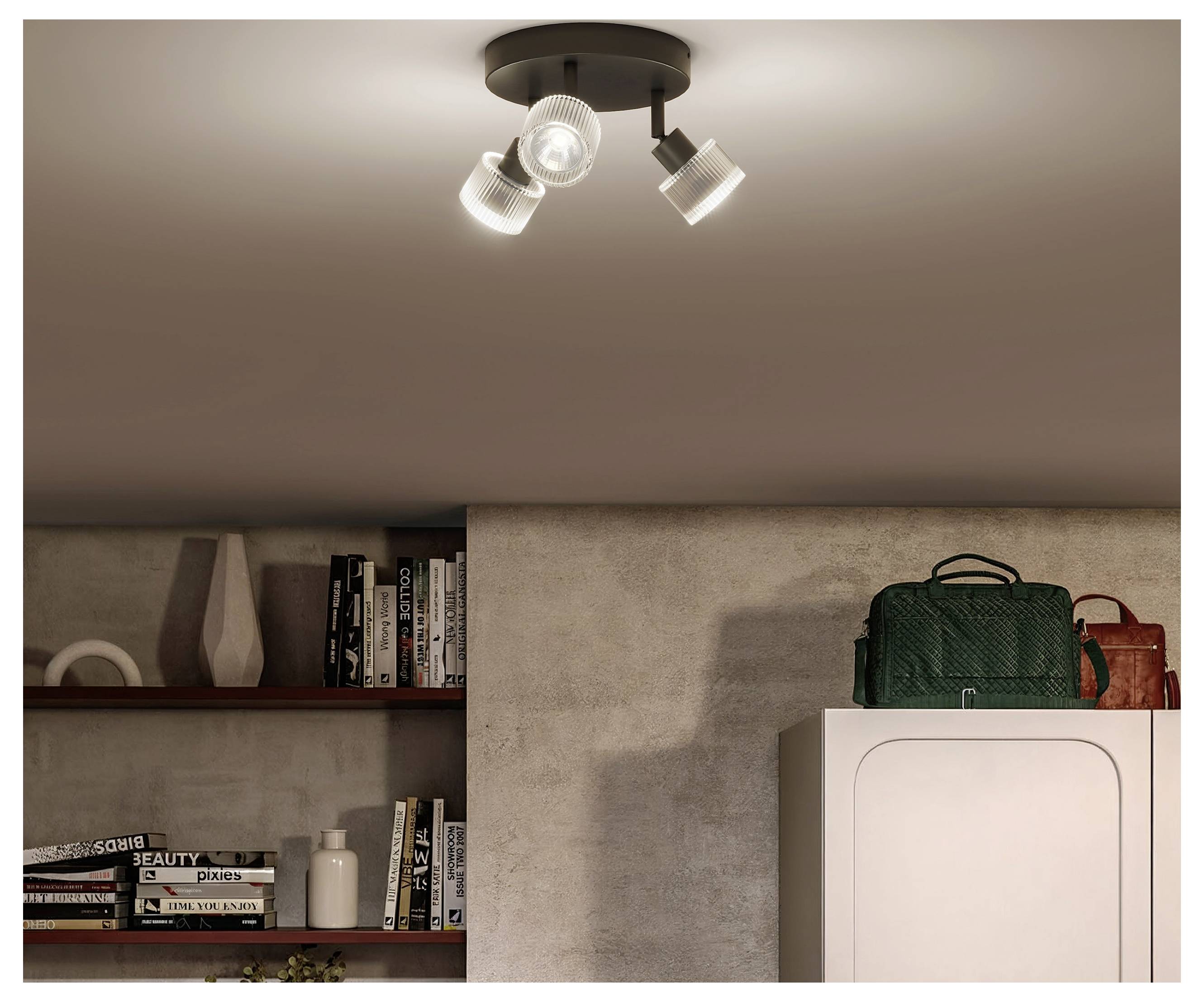 Interior room with ceiling spotlight, built-in shelves of books and decor, and a cabinet topped with green and red bags<br>