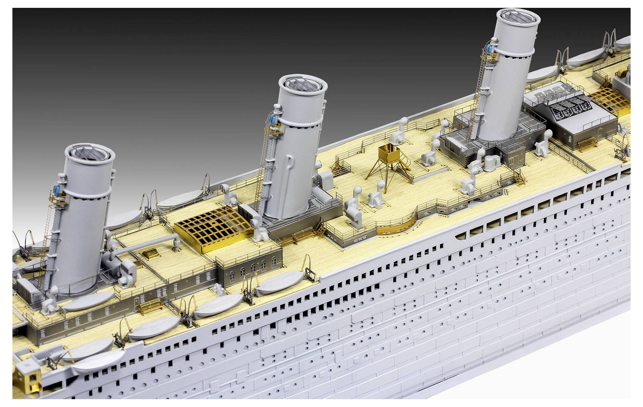 Detailed model of a ship deck showing three large smokestacks, lifeboat housings, and deck machinery on a white ocean liner.