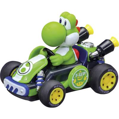 Toy Yoshi figure driving a green and black Mario Kart-style race car with 1-UP and Red Shell decals on the wheels.<br>