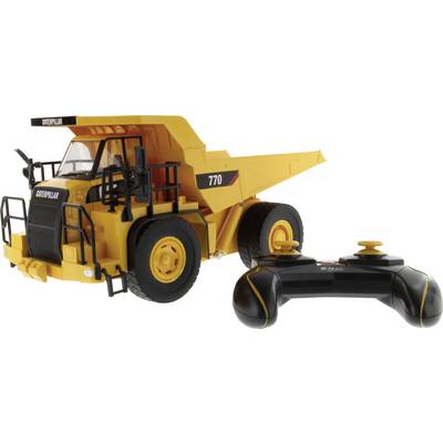 Remote-controlled Caterpillar 770 dump truck toy with a black-and-yellow controller on a white background.