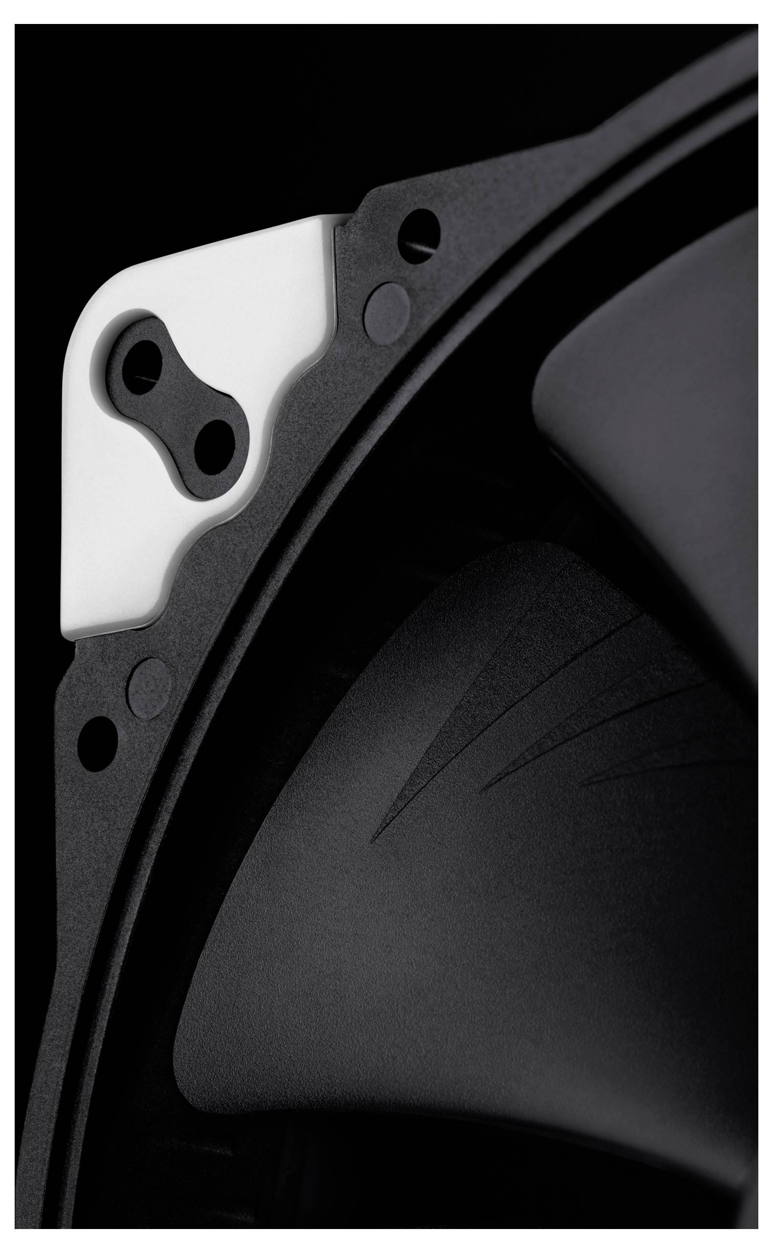 Close-up of a black and silver mechanical component with screws and curved housing, shown in extreme detail against a dark background.