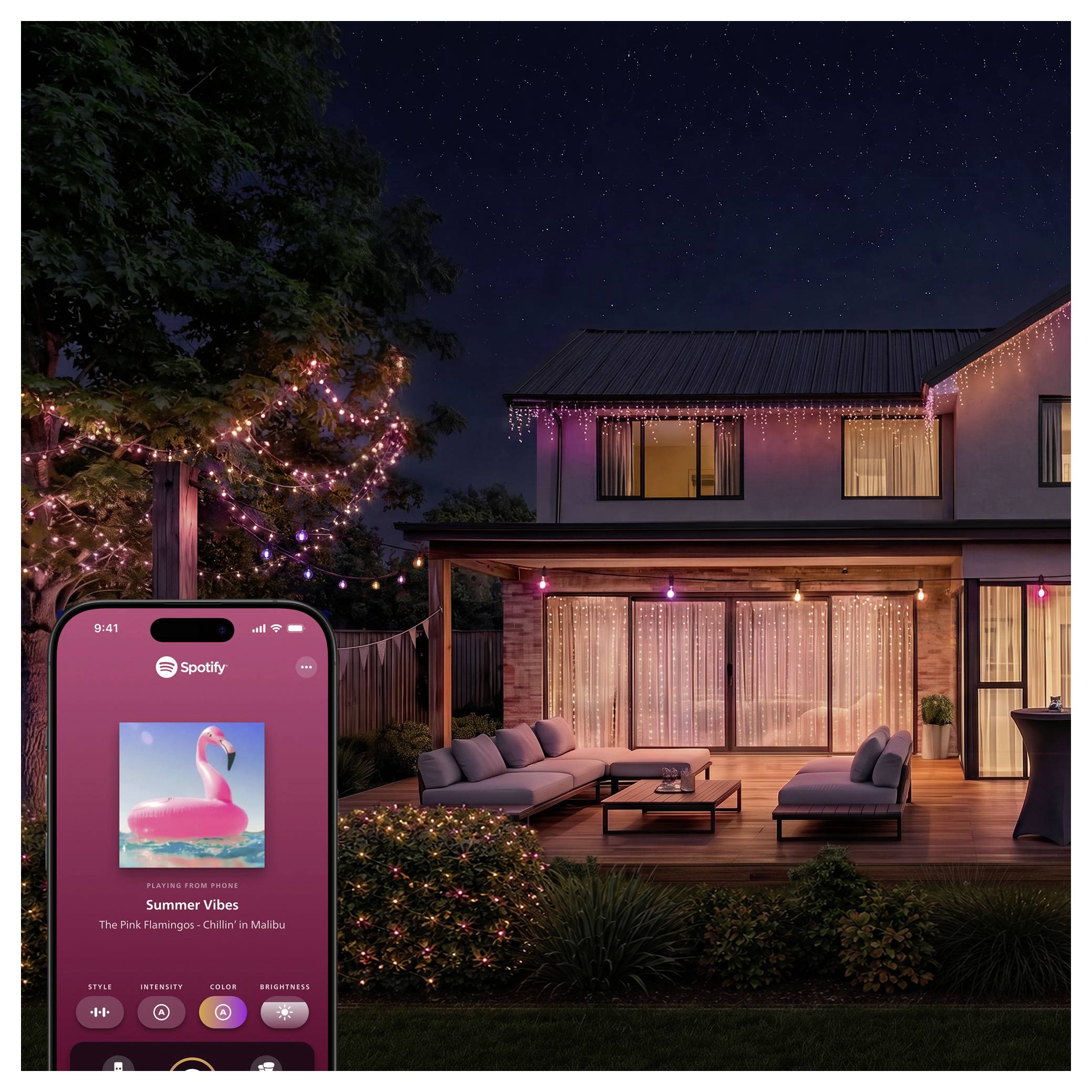 Lit backyard patio at night with string lights and a phone showing Spotify 'Summer Vibes' playlist cover art of a pink flamingo.