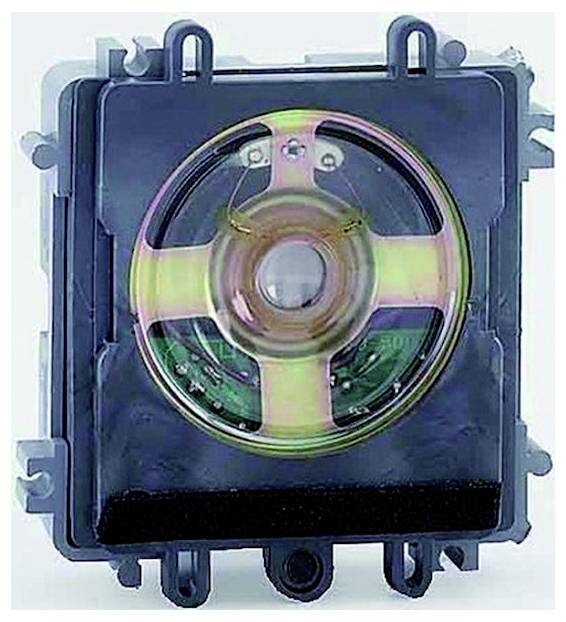 Close-up of a circular electronic component or speaker-like device in a black square housing with mounting tabs and visible internal circuitry.