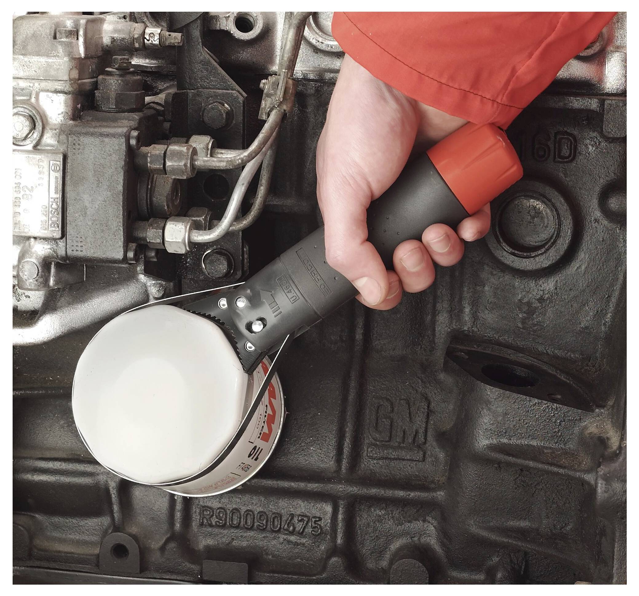 Hand holding a tool-like oil filter against an engine block, suggesting automotive maintenance or oil filter installation.