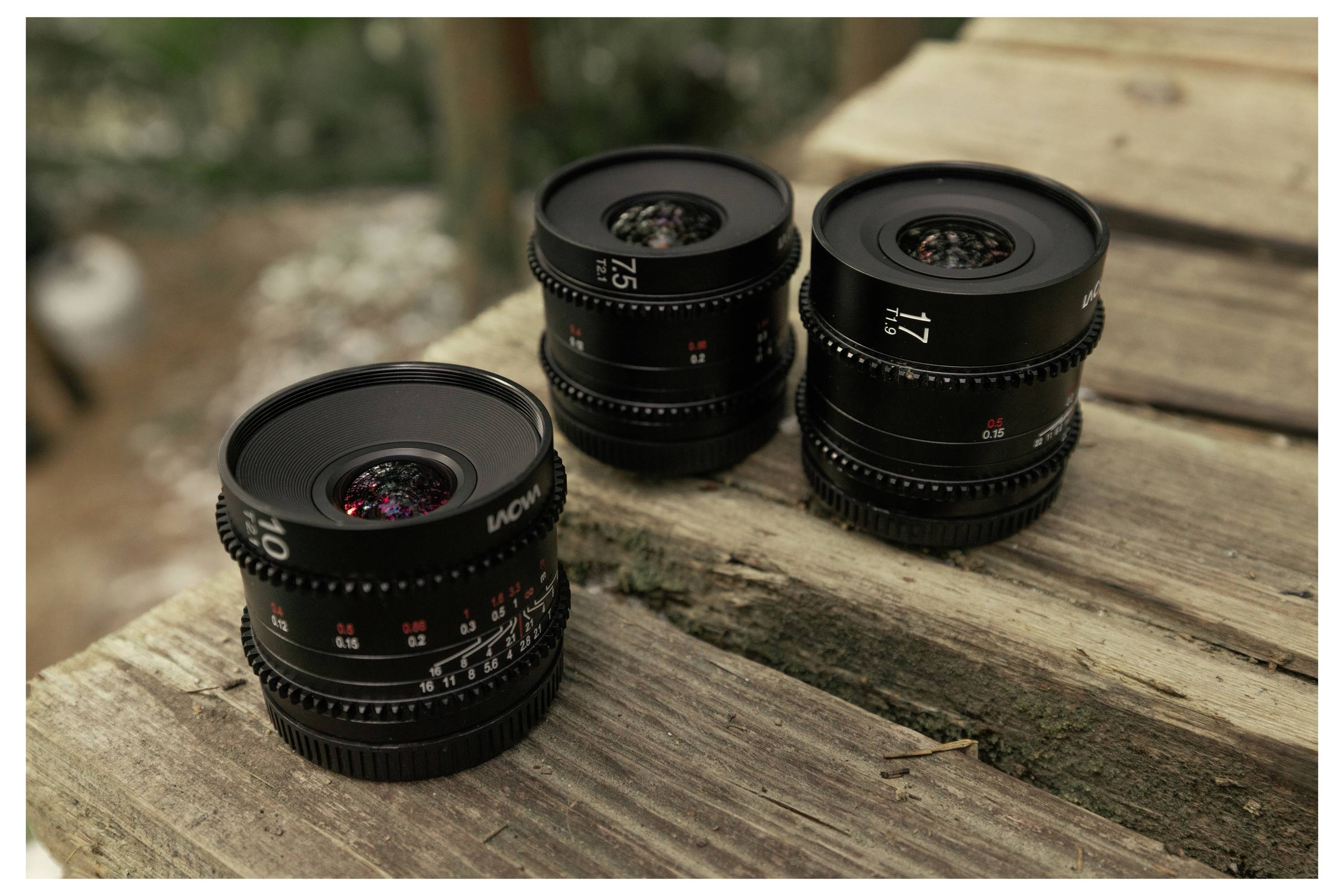Three camera lenses arranged on a weathered wooden surface outdoors.