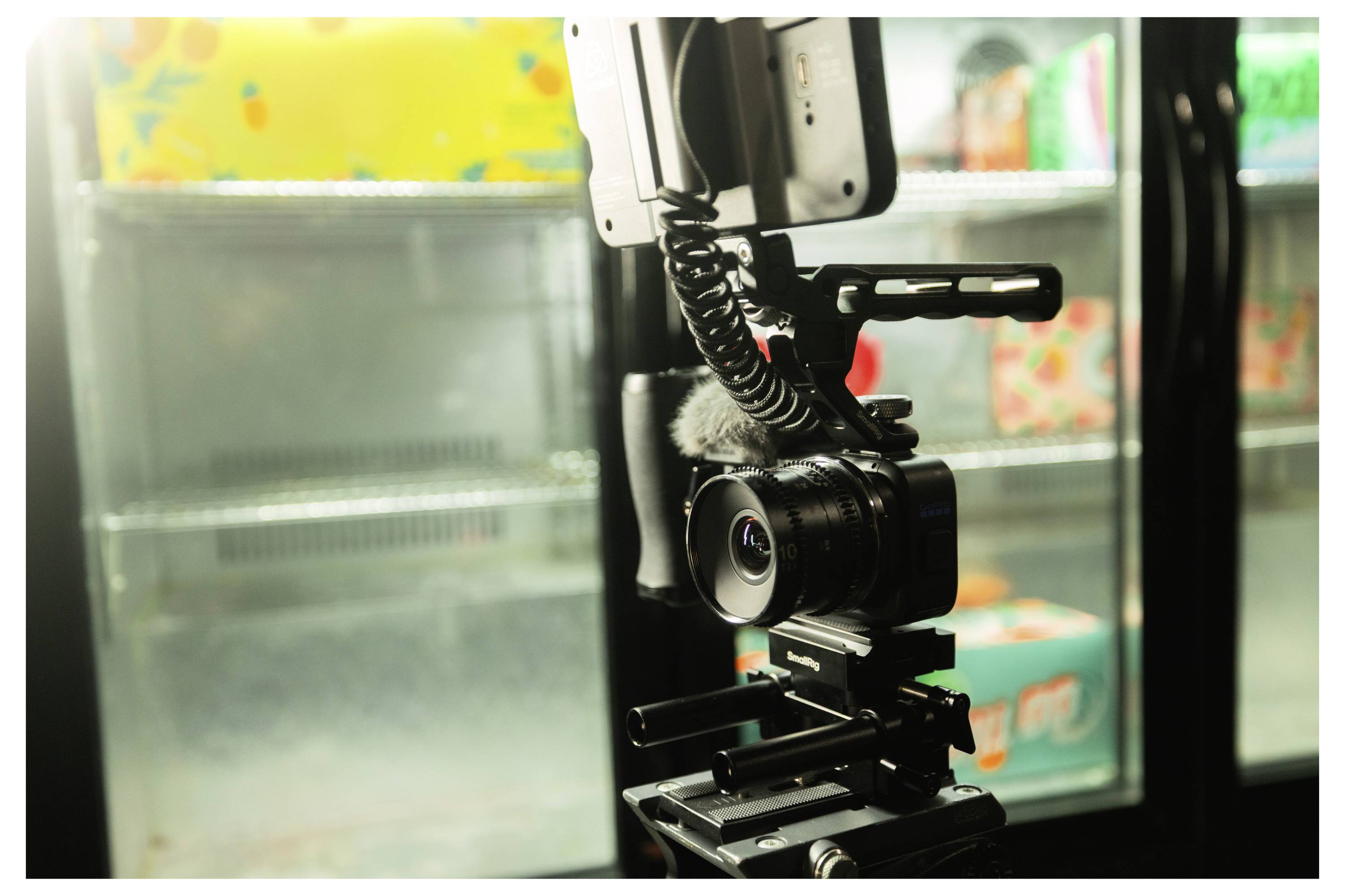A camera mounted on a rig beside a glass-door refrigerator, filming the shelves inside a store.