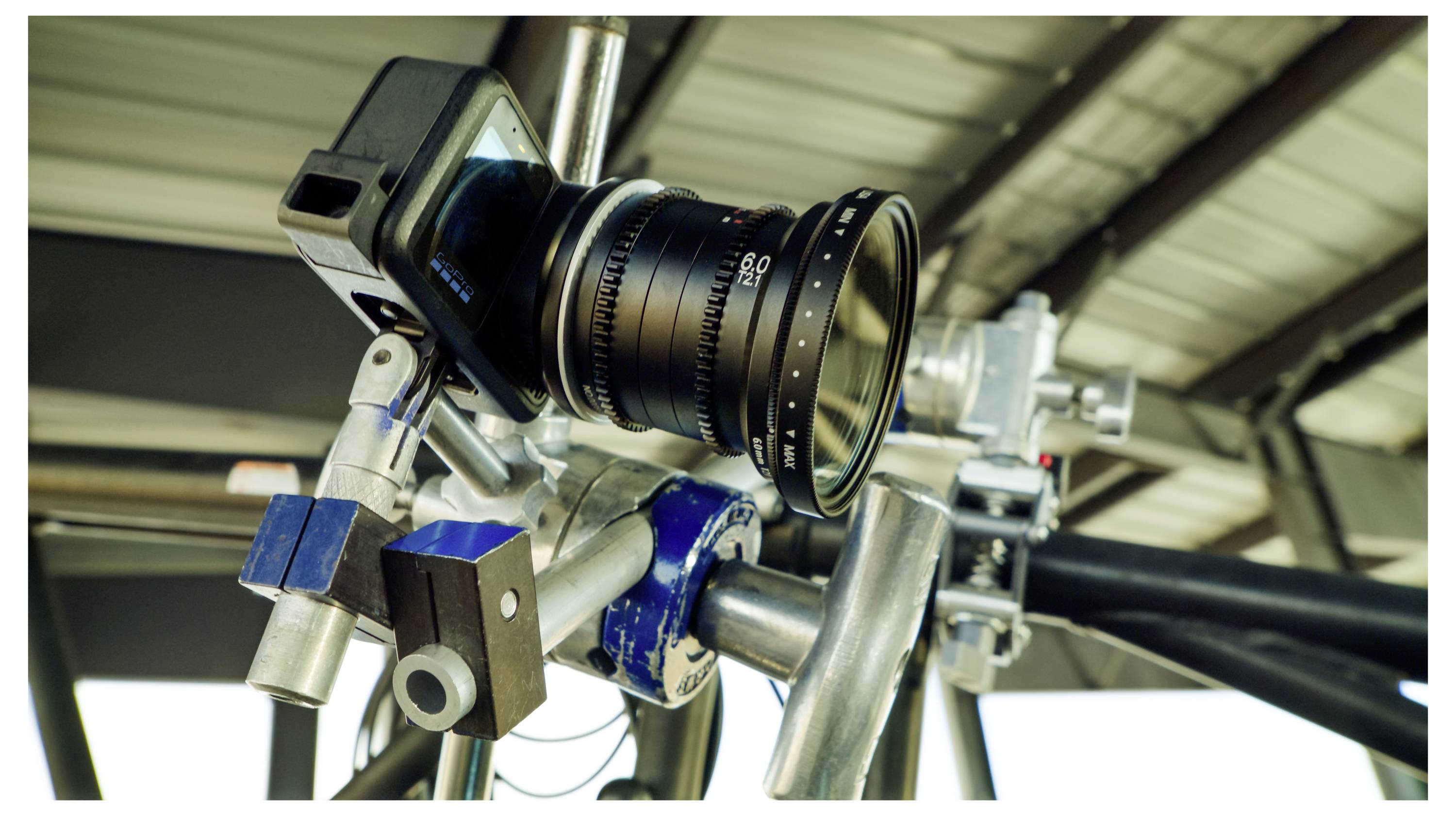 Close-up of a camera mounted on a metal rig, with a large lens attached for filming or photography.