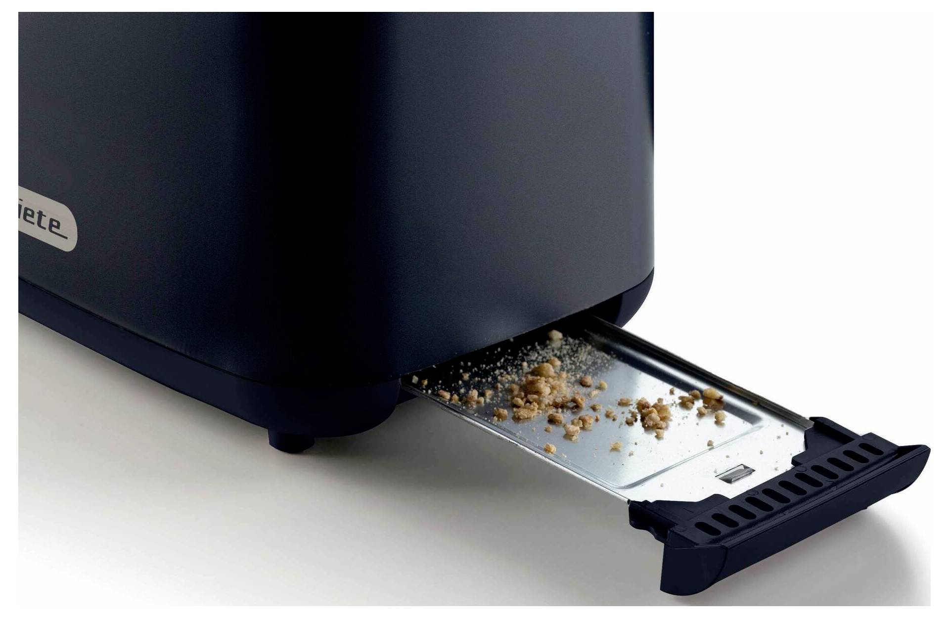Close-up of a vacuum cleaner base with its slide-out dirt tray open, showing collected dust and crumbs being emptied.