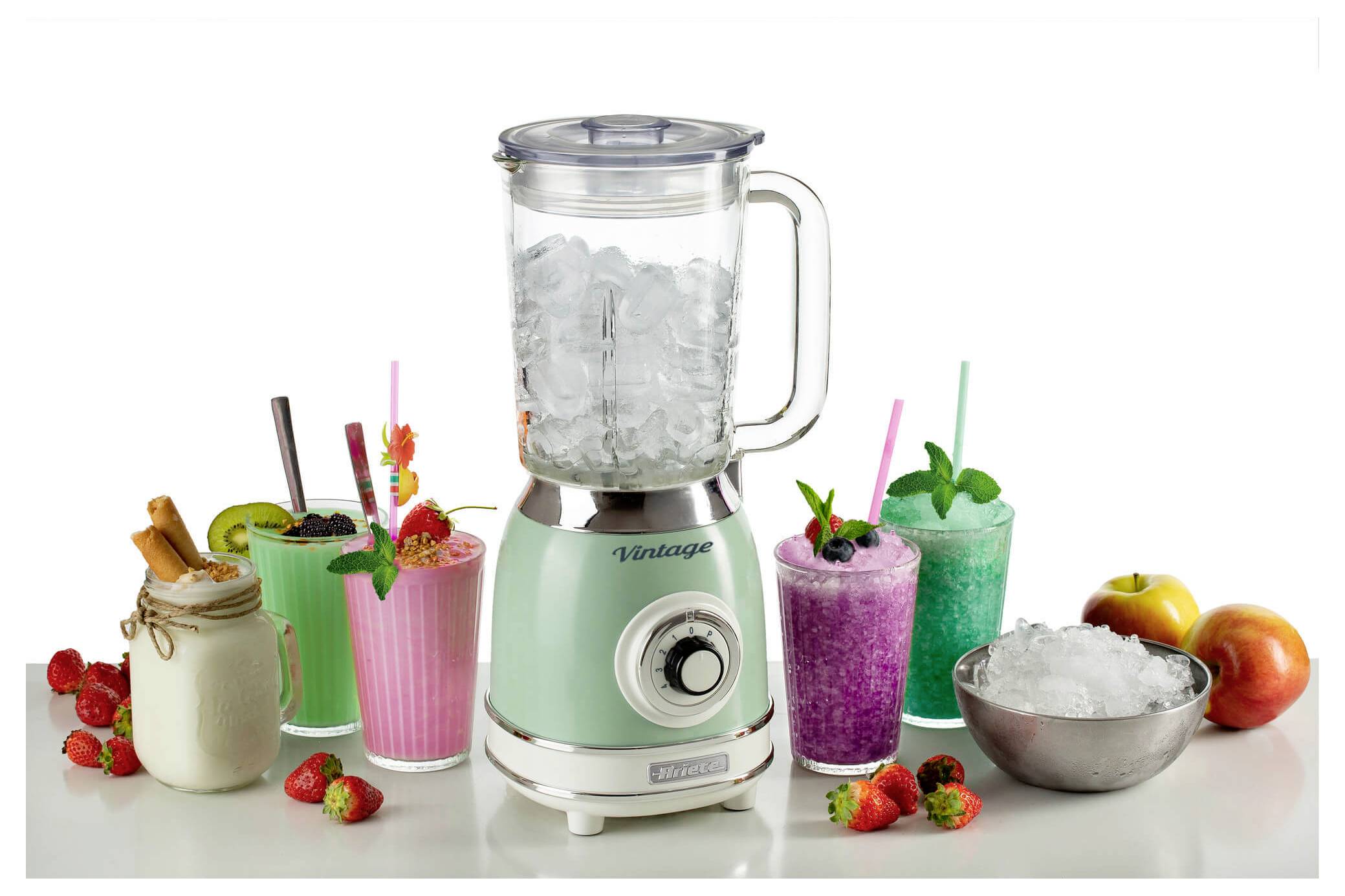 Mint-green blender filled with ice on a counter, surrounded by several colorful fruit and smoothie drinks, strawberries, kiwi, mint, and peaches.
