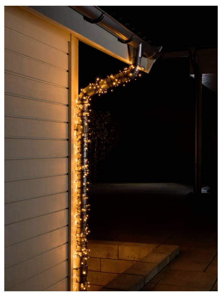 A house corner and gutter outlined with warm orange string lights at night, illuminating the side of a home and patio area.