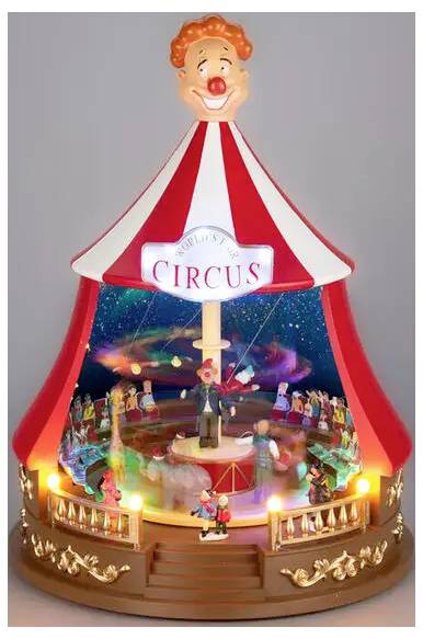 A circus-themed tabletop display with a clown-topped red-and-white tent, 'CIRCUS' sign, and colorful miniature performers around a lit central ring.<br>