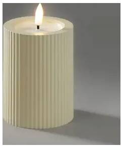 Lit cream-colored ribbed pillar candle on a gray background