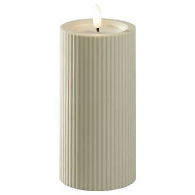 Lit beige ribbed pillar candle on a white background