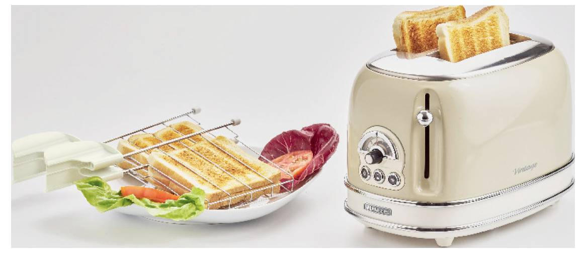 A toaster with two slices of toast pops up beside a plate of toasted bread, salad greens, and slices of salami.