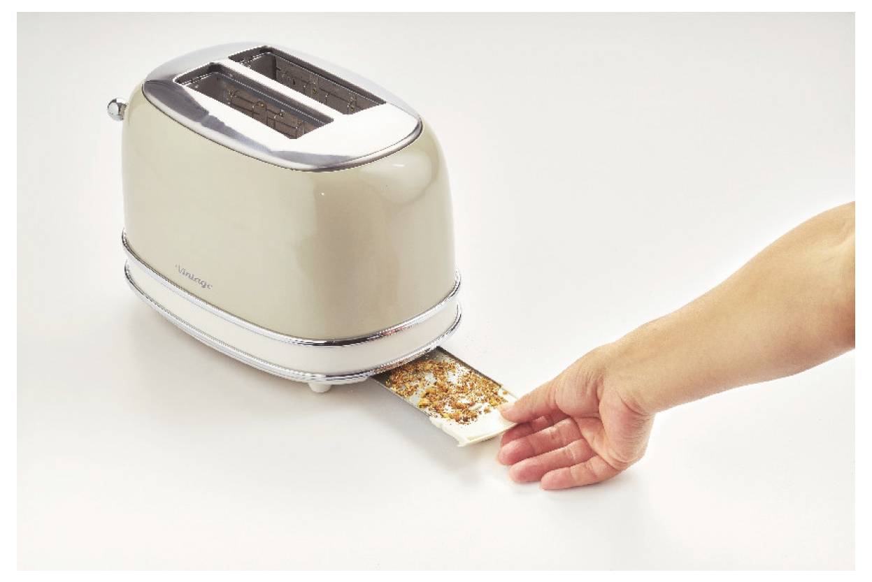Hand inserting a slice into a two-slot toaster with a piece that looks burnt or dirty, suggesting unsafe or damaged food handling.