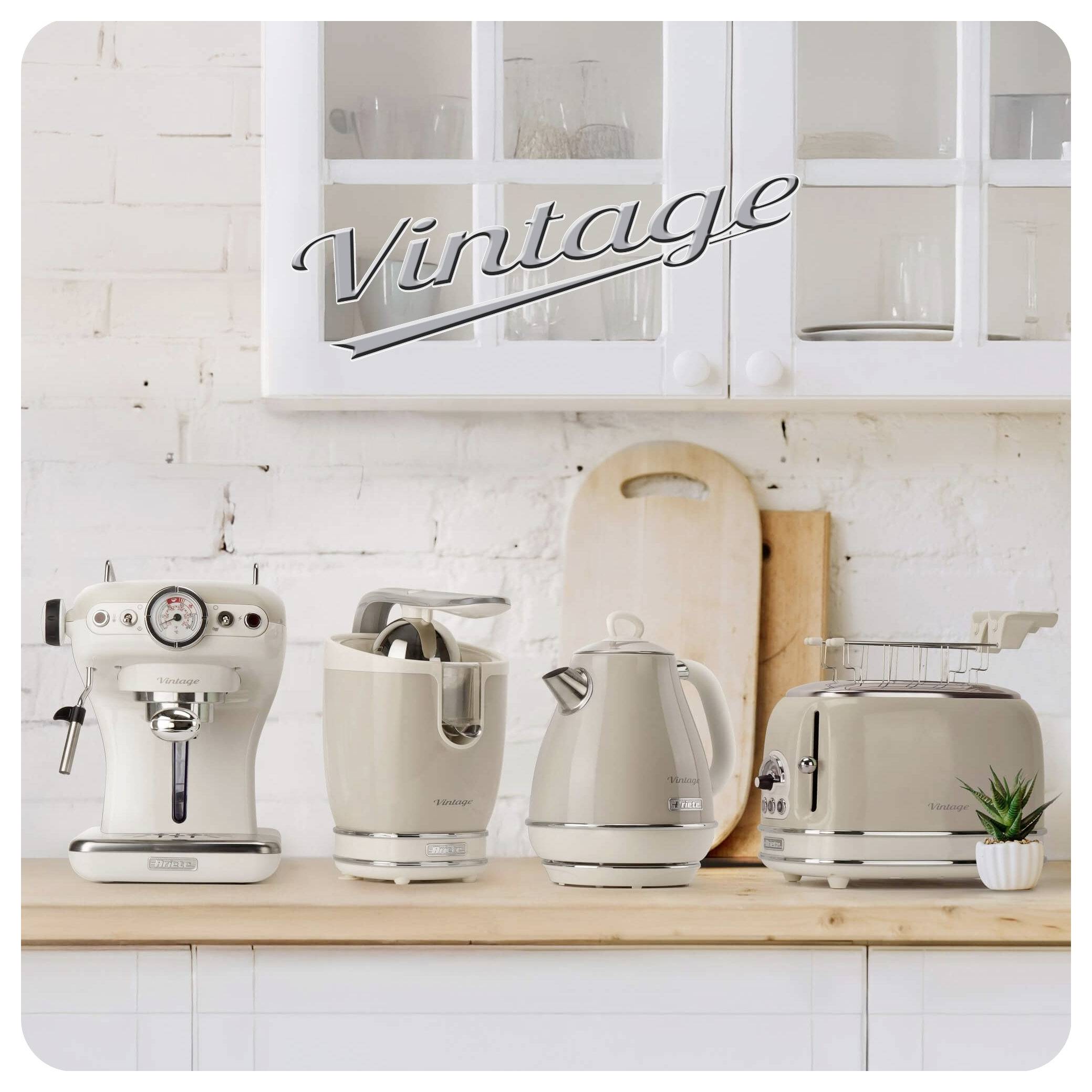Vintage-style kitchen counter with a coffee machine, blender, kettle, and toaster beneath white cabinets and a 'Vintage' sign.