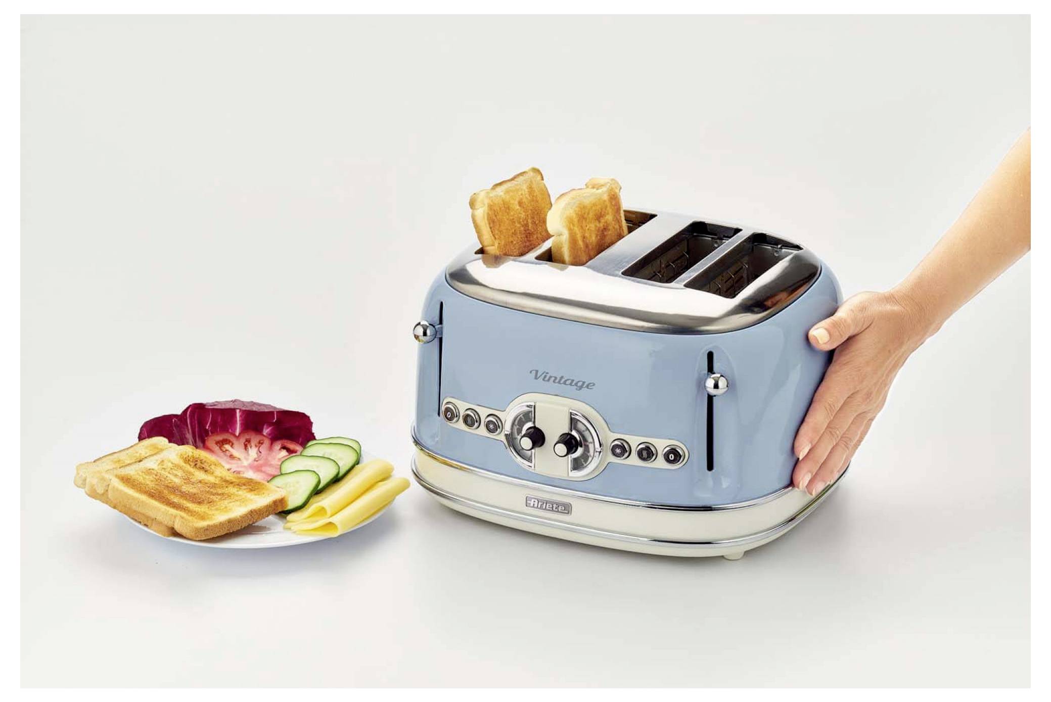 Blue four-slot toaster with two slices popping up beside a plate of toasted bread and sliced cucumber, showing breakfast serving.