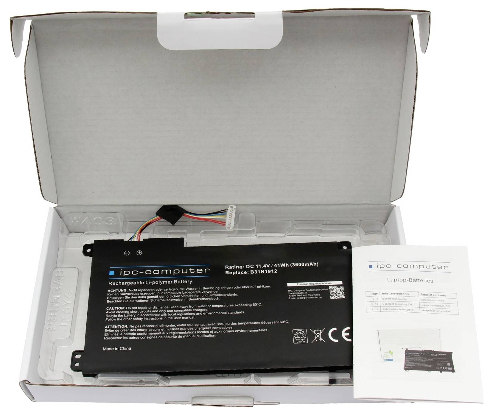 Open box containing a laptop replacement battery, with the battery pack, wiring, and instruction leaflet visible inside.