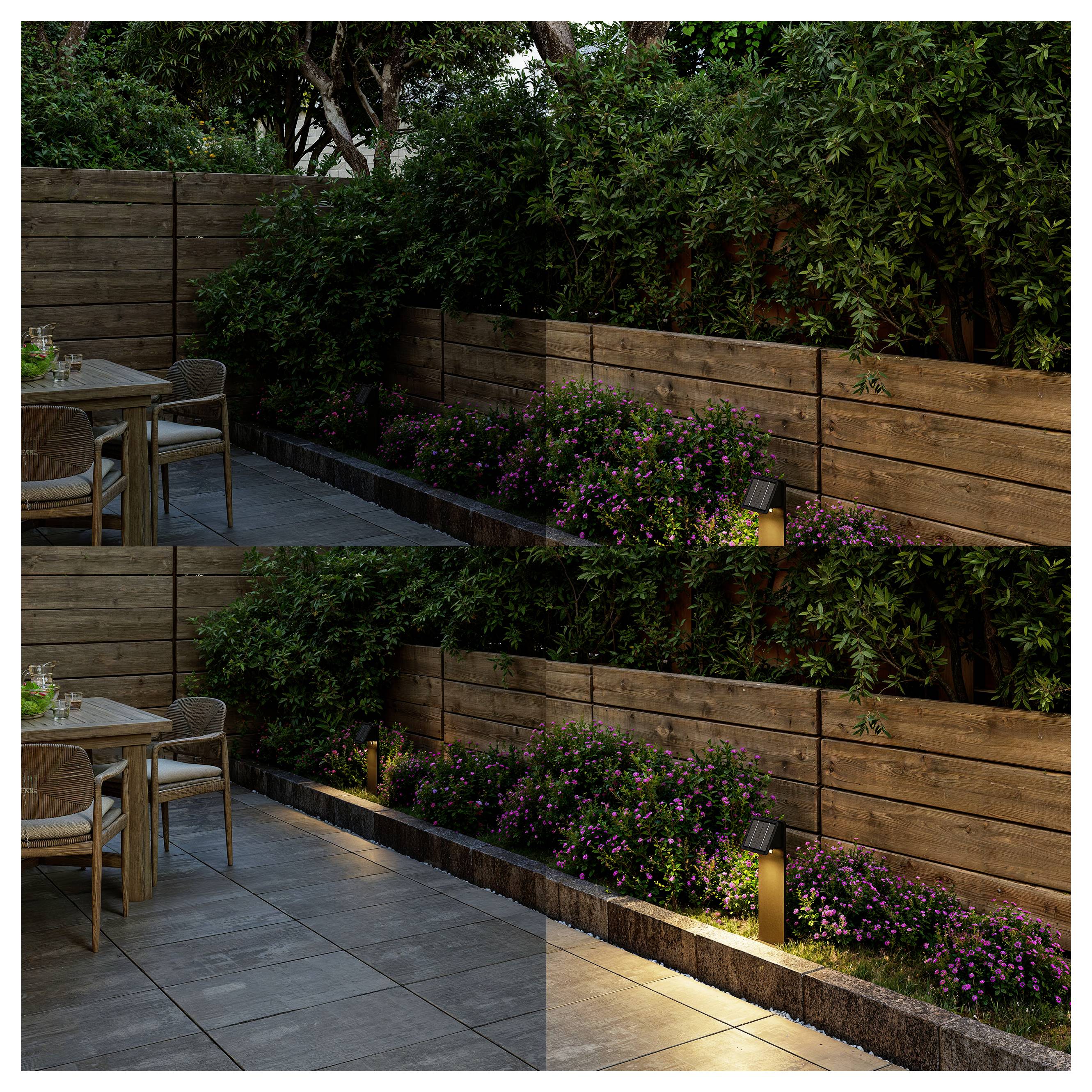 Modern patio with wooden privacy fence, lush greenery, pink flowers, and soft ground lighting beside a small outdoor dining set<br>