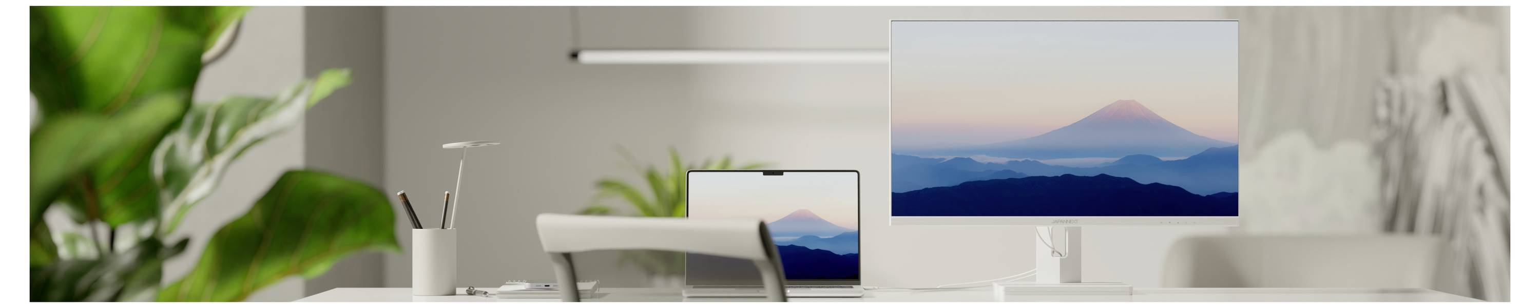 Modern desk setup with two monitors and a large wall display showing a blue mountain landscape, suggesting a calm workspace.<br>
