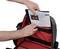 A black and red open bag is shown, with papers being placed inside it.