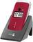 A red flip mobile phone displaying the time '12:00' on its front screen, positioned in a black charging dock.