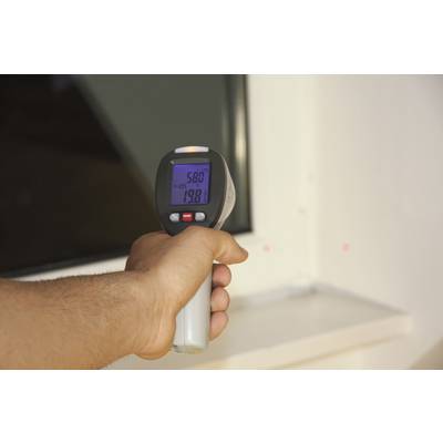 A hand is holding an infrared thermometer pointed at a surface. The display shows '58.0°C'.