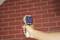 A hand holds an infrared thermometer in front of a red brick wall, displaying a temperature of 22.1 degrees Celsius.