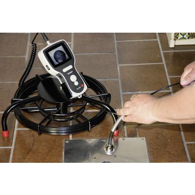 A person is using a pipe inspection endoscope to check a drain. The screen displays an image of the inside of the pipe.
