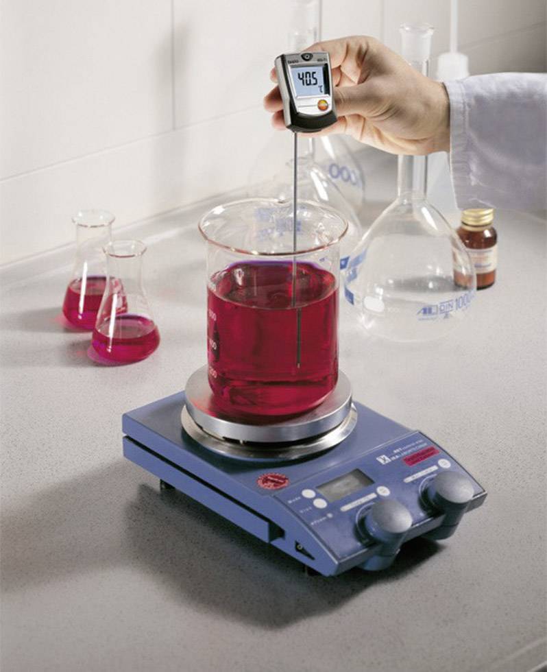 A person is measuring the temperature of a red liquid in a beaker sitting on a hotplate. The display shows 40.5°C.