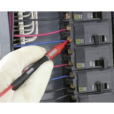 A gloved hand holds a voltage tester pen at a circuit breaker in an electrical fuse box for voltage testing.