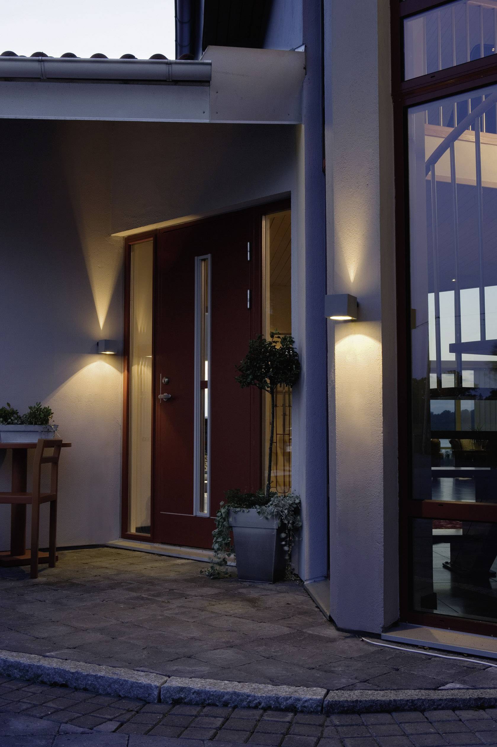 Entrance area of a modern house at dusk, with subdued exterior lighting creating a warm ambience.