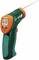 An infrared thermometer displays '617' on a digital display. A red laser beam is pointing at the measurement area.