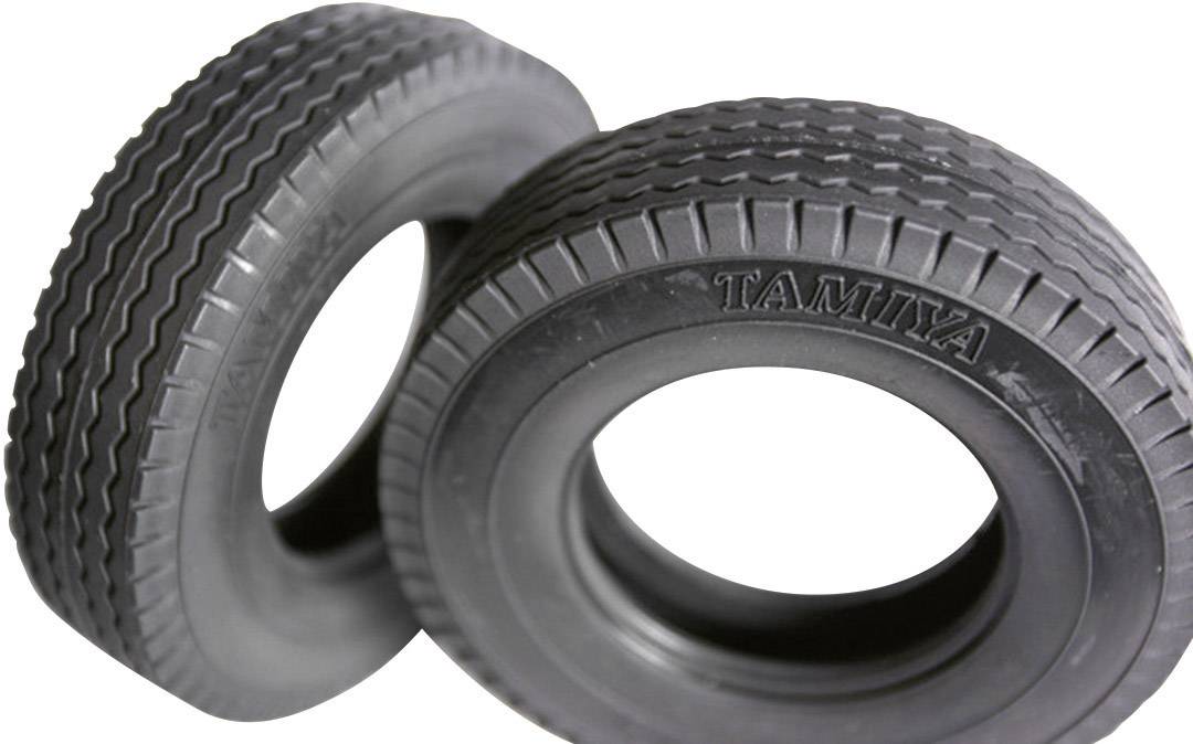 Two black model tyres, one with grooves and the other with a block tread pattern, both marked with the 'Tamiya' logo.