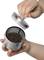 A hand holds a tea strainer with black tea, while the other hand places the lid on top.