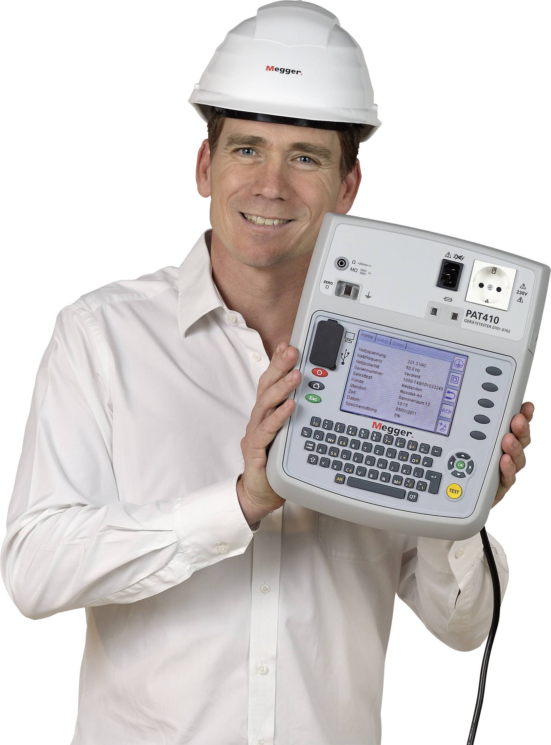 A man in a white shirt and hard hat is holding an electrical testing device in his hand and smiling. The device displays a digital readout.