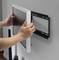A person is mounting a flat-screen monitor to a wall bracket. The screen is being held with both hands as it slides into the mounting bracket.