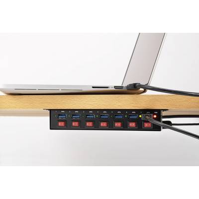 A laptop is connected to a USB hub with multiple ports and switches, which is mounted underneath a wooden table.