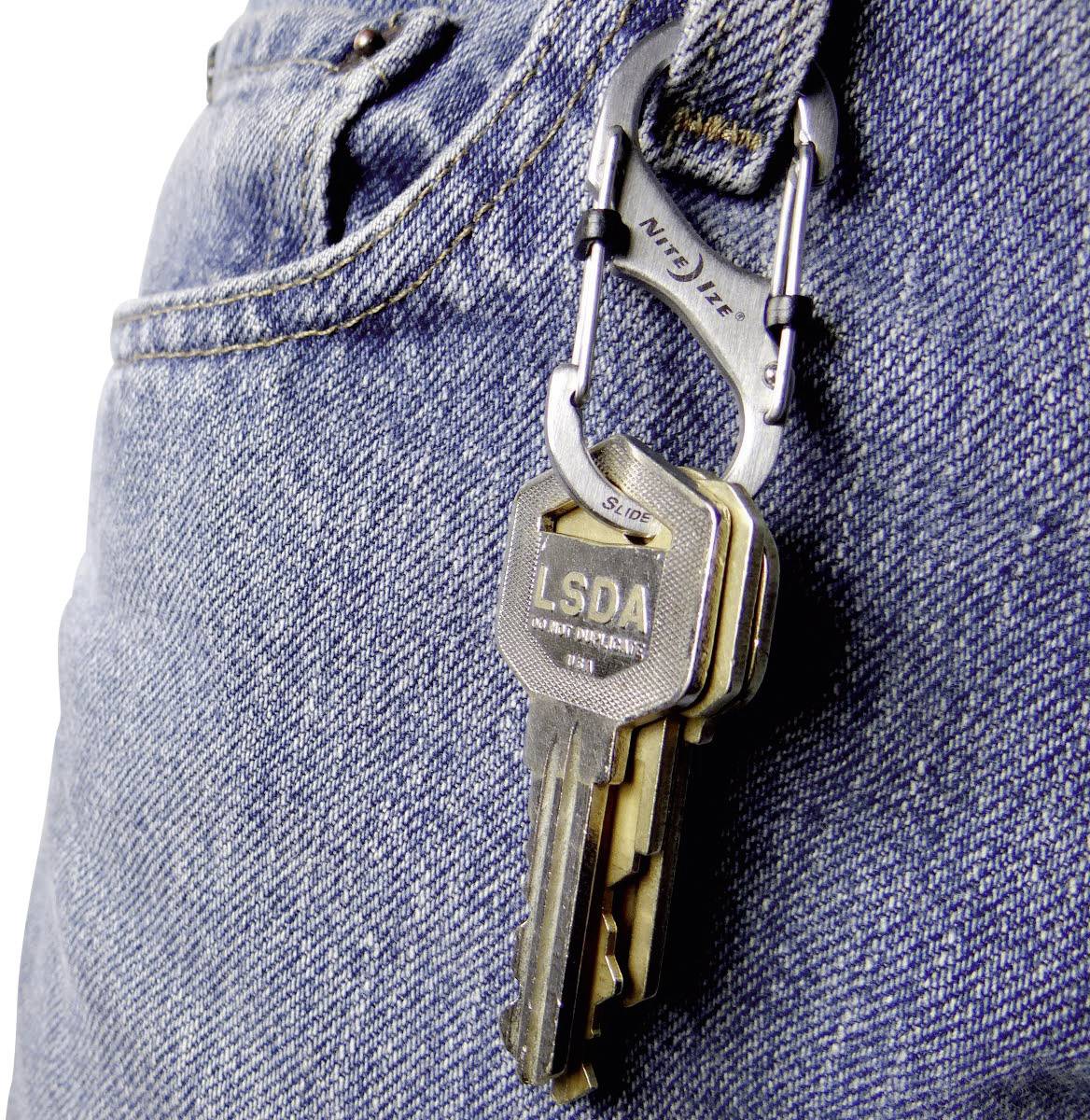 A carabiner clip hangs from a jean belt loop, holding several metal keys marked 'LSDA'.