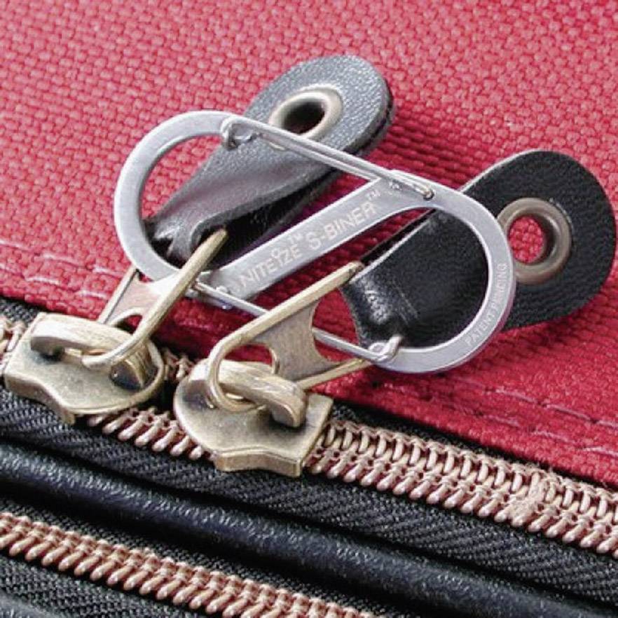 Red suitcase with two zip pulls secured by a metal S-biner to prevent opening.