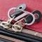 Red suitcase with two zip pulls secured by a metal S-biner to prevent opening.