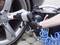 A person is tightening a wheel nut of a car tyre with a pneumatic impact wrench.