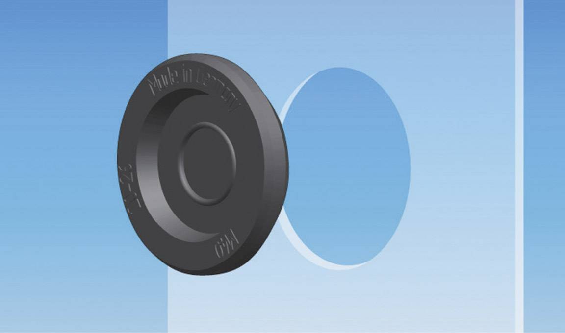 A round, black rubber buffer with a central depression sits on a smooth blue wall.
