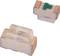 Two small white components with a green marking, presumably electronic parts, on a white background.