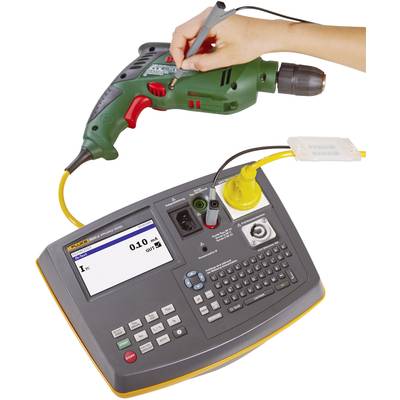 A hand is testing a green drill with a portable electrical testing device. The display shows a measured value and offers button inputs.